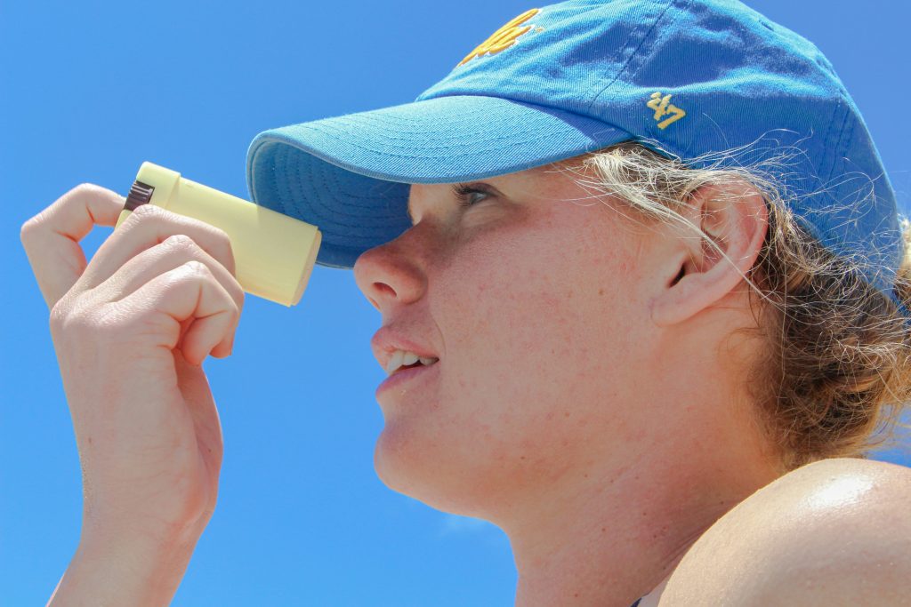 Woman applying mineral sunscreen with zinc oxide on face outdoors