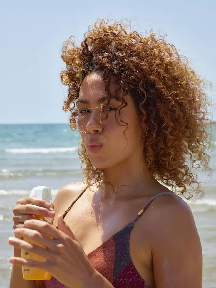 Woman applying sunscreen at the beach on a sunny summer day