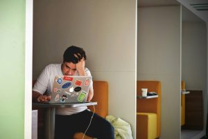 Stressed man working on laptop showing how stress impacts overall health and skin.